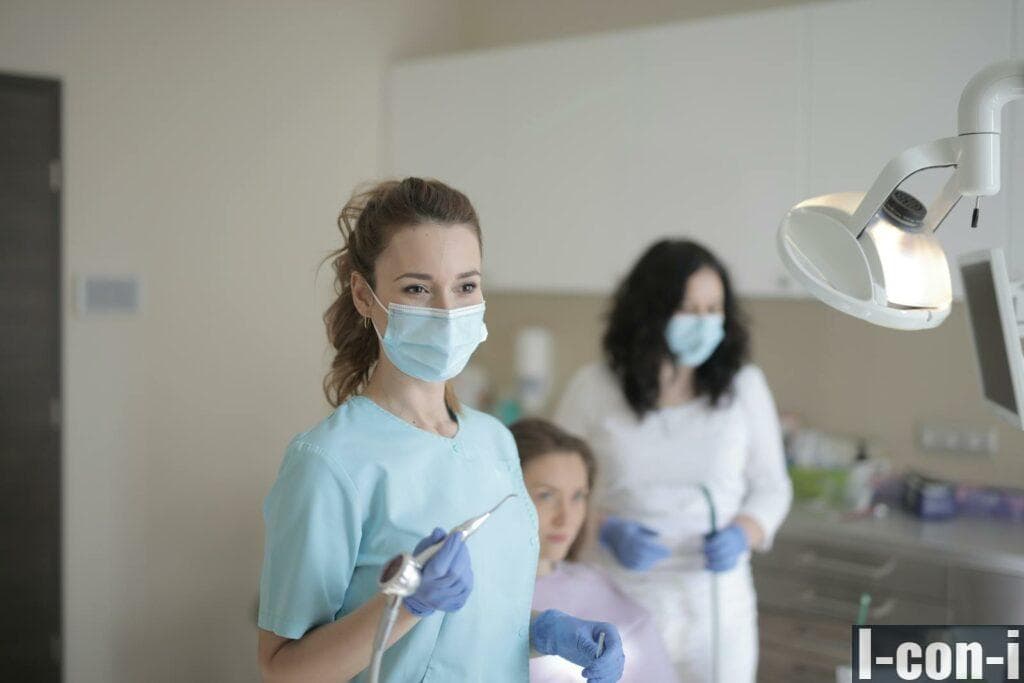 Young female dentist working with assistant while treating patient in modern hospital