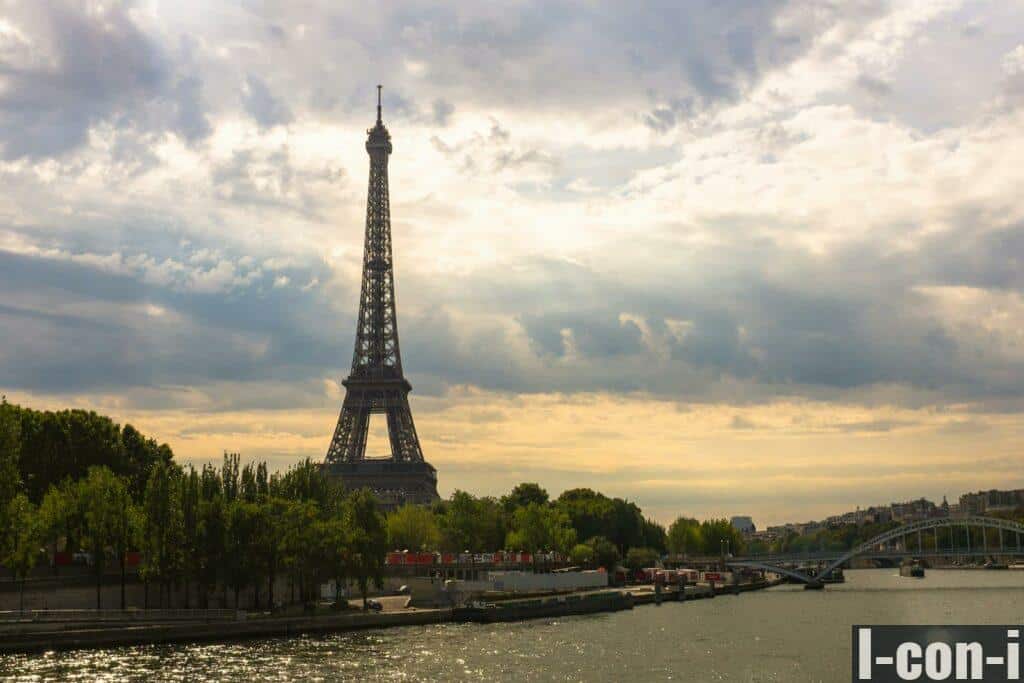 Stunning view of the Eiffel Tower at sunset with the River Seine and lush green trees.