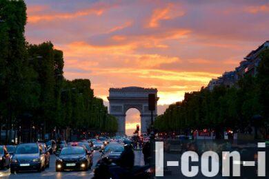 Vivid sunset sky over Arc de Triomphe, capturing Parisian traffic and architecture.