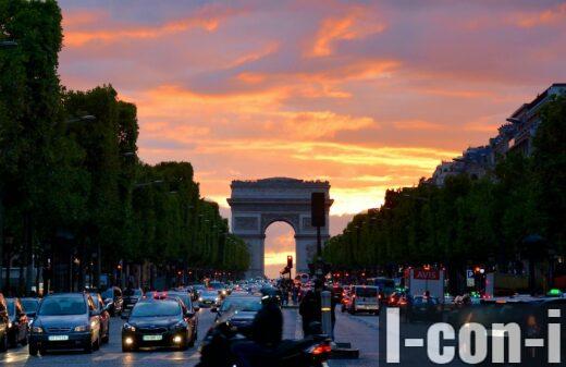 Vivid sunset sky over Arc de Triomphe, capturing Parisian traffic and architecture.