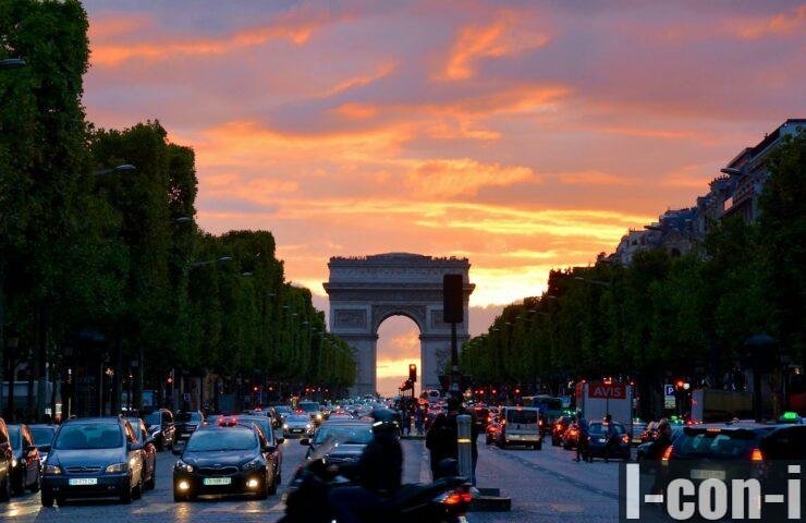 Vivid sunset sky over Arc de Triomphe, capturing Parisian traffic and architecture.