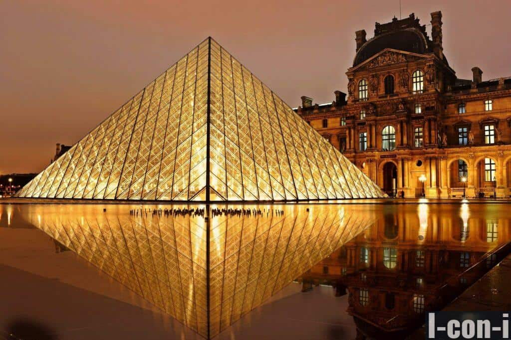 Stunning nighttime view of the illuminated Louvre Pyramid and reflection in Paris, France.